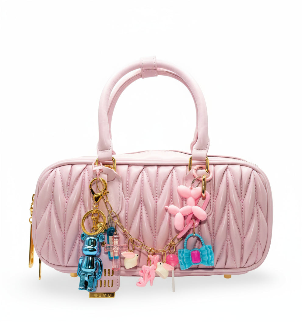 A pink handbag with a custom-made chain charm featuring various rabbit-themed figures and other small decorative items.